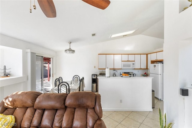 interior space with ceiling fan, white appliances, lofted ceiling with skylight, hanging light fixtures, and white cabinets