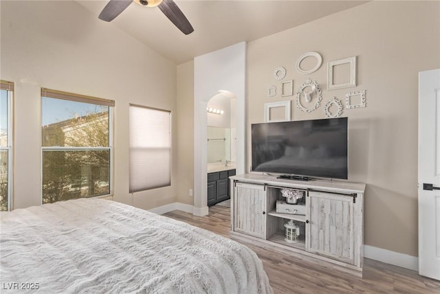 bedroom featuring light wood-type flooring, ceiling fan, ensuite bathroom, and high vaulted ceiling