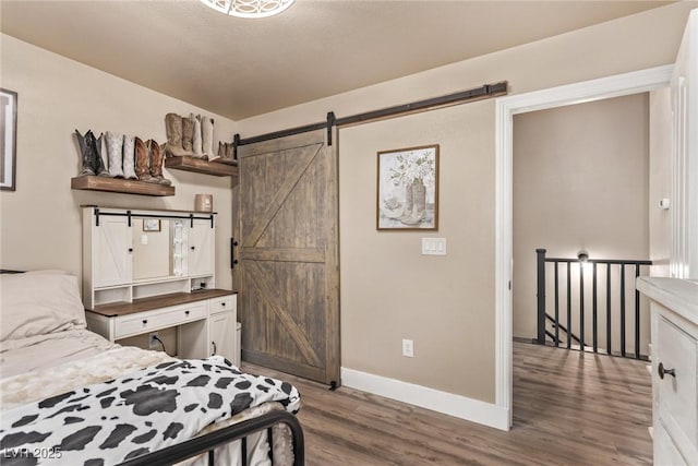 bedroom featuring a barn door and dark hardwood / wood-style flooring