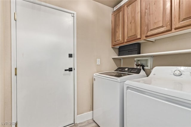 laundry room with cabinets, washer and clothes dryer, and light hardwood / wood-style flooring