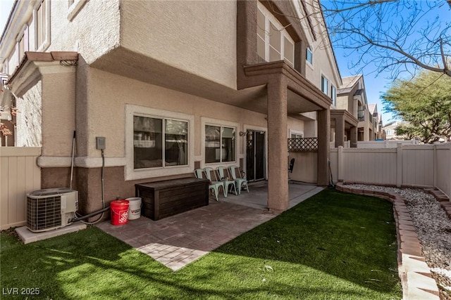 rear view of house with cooling unit, a lawn, and a patio