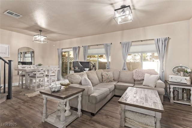 living room featuring dark wood-type flooring, a textured ceiling, and an inviting chandelier