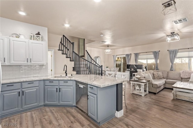 kitchen featuring stainless steel dishwasher, wood-type flooring, sink, white cabinetry, and gray cabinetry