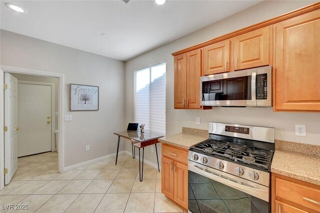 kitchen featuring light tile patterned floors, appliances with stainless steel finishes, and light stone counters