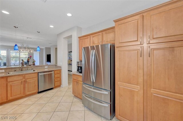 kitchen featuring appliances with stainless steel finishes, sink, hanging light fixtures, light stone counters, and light tile patterned floors