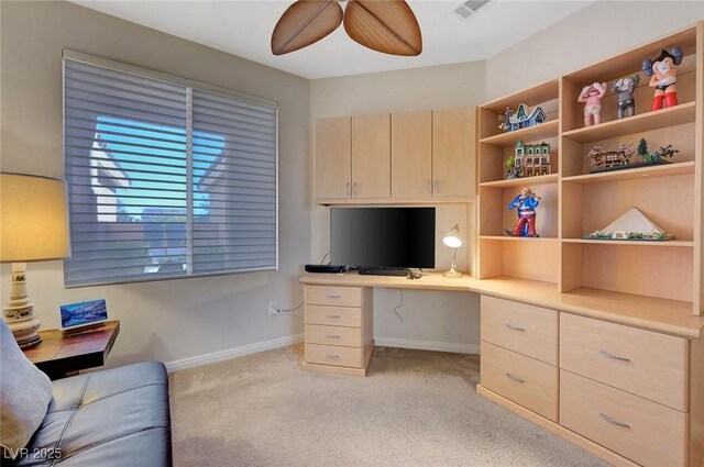 carpeted office featuring ceiling fan and built in desk