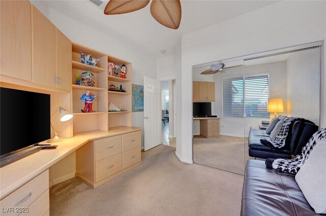 home office with ceiling fan, light colored carpet, and built in desk