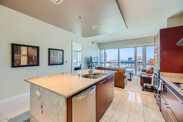 kitchen with light stone countertops, sink, a kitchen island with sink, and stainless steel appliances