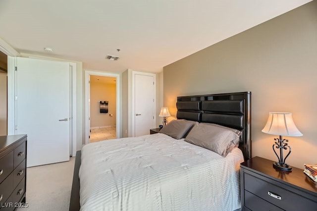 bedroom featuring ensuite bathroom and light colored carpet