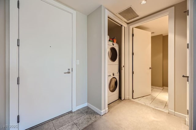 laundry room featuring stacked washer and clothes dryer and light tile patterned flooring