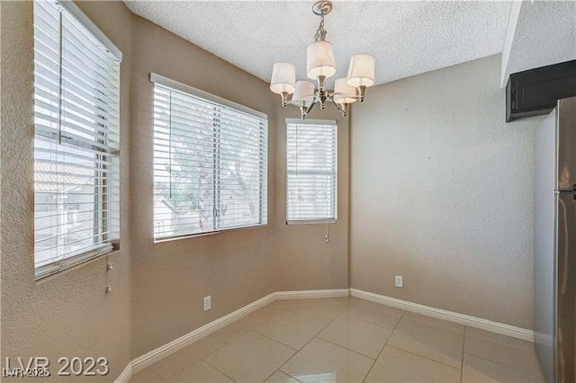 spare room featuring a notable chandelier, tile patterned floors, and a textured ceiling