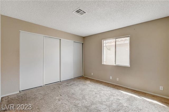 unfurnished bedroom with a textured ceiling, a closet, and light colored carpet