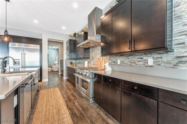 kitchen featuring decorative light fixtures, backsplash, range hood, dark brown cabinetry, and stainless steel appliances