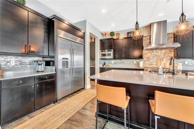 kitchen featuring a kitchen bar, decorative backsplash, appliances with stainless steel finishes, and extractor fan