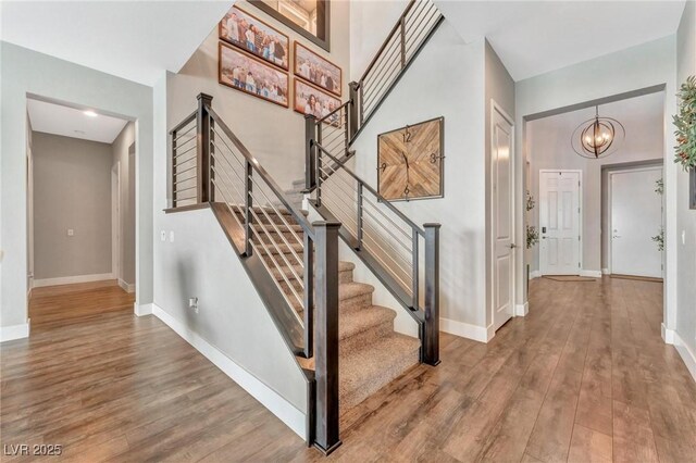 stairs featuring hardwood / wood-style floors and an inviting chandelier