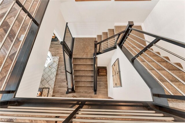 stairway with wood-type flooring and a high ceiling