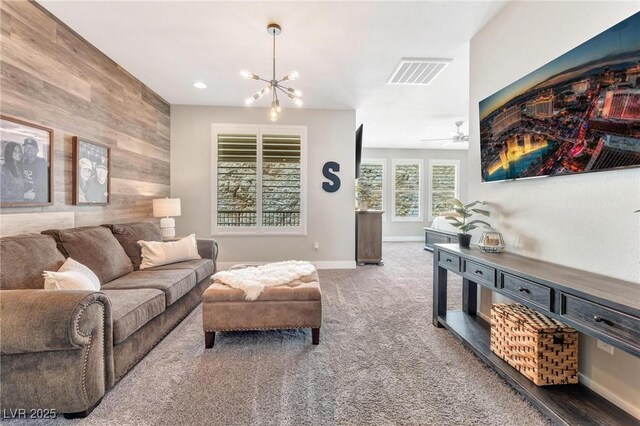 living room with carpet flooring, ceiling fan with notable chandelier, and wooden walls