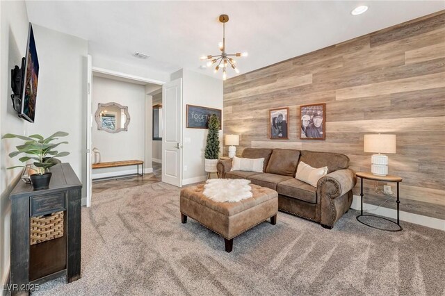 living room with carpet floors, wood walls, and a notable chandelier