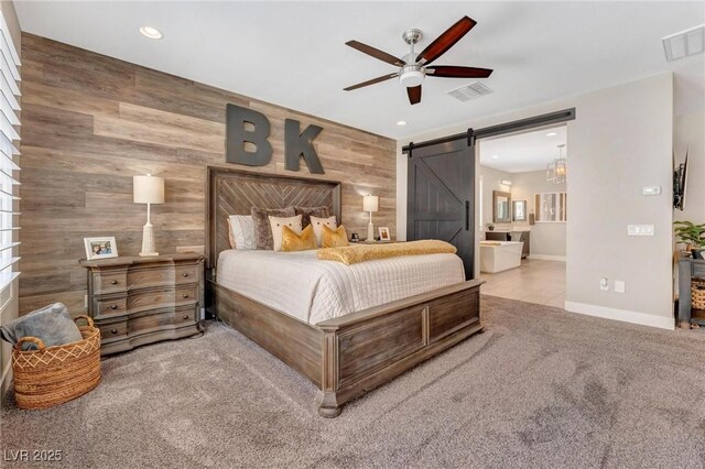 bedroom with ceiling fan, ensuite bath, wood walls, and a barn door