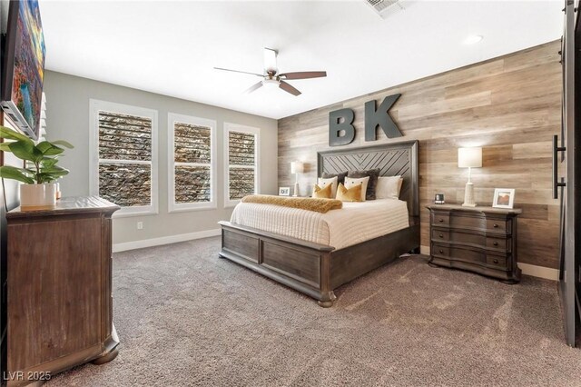 bedroom featuring ceiling fan, wood walls, and carpet flooring