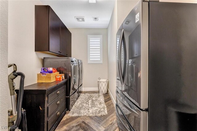 clothes washing area featuring wood-type flooring, washer and dryer, and cabinets