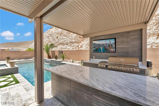 view of patio with a mountain view, a fenced in pool, an outdoor kitchen, and area for grilling