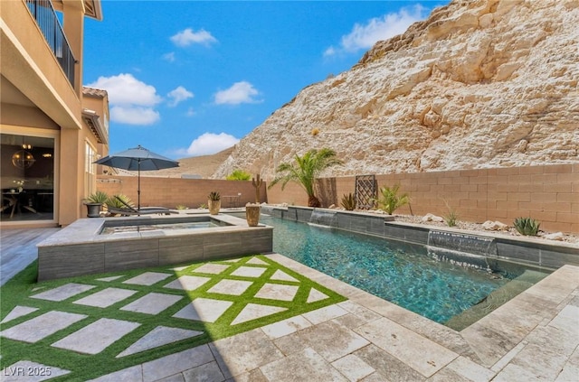 view of swimming pool featuring pool water feature, a patio area, a mountain view, and an in ground hot tub