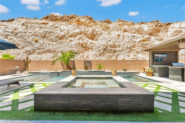 view of swimming pool with an in ground hot tub, a multi sided fireplace, a mountain view, and a patio area