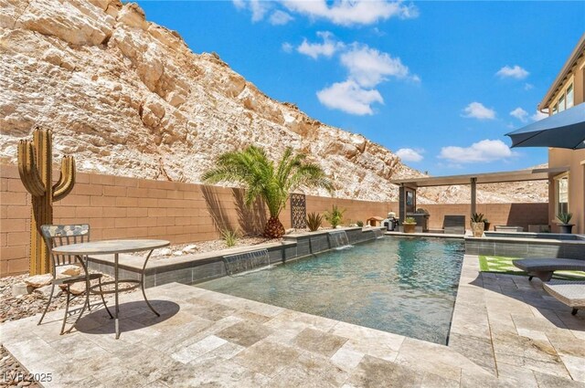 view of pool with pool water feature, a mountain view, and a patio