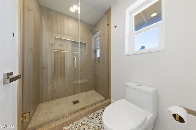 bathroom featuring a shower with shower door, tile patterned floors, and toilet