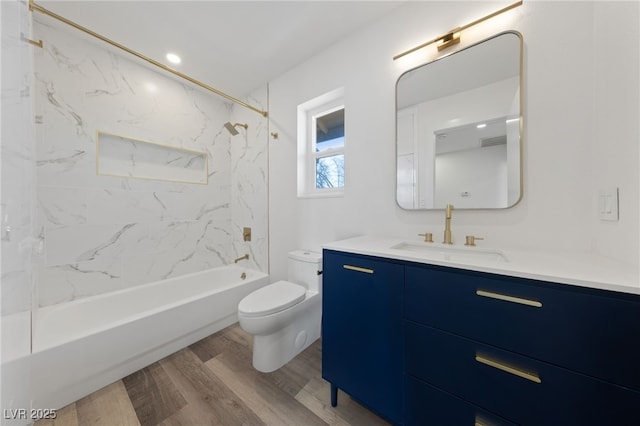 full bathroom featuring hardwood / wood-style floors, tiled shower / bath combo, vanity, and toilet