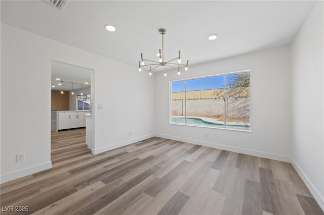 unfurnished dining area with hardwood / wood-style floors and a notable chandelier