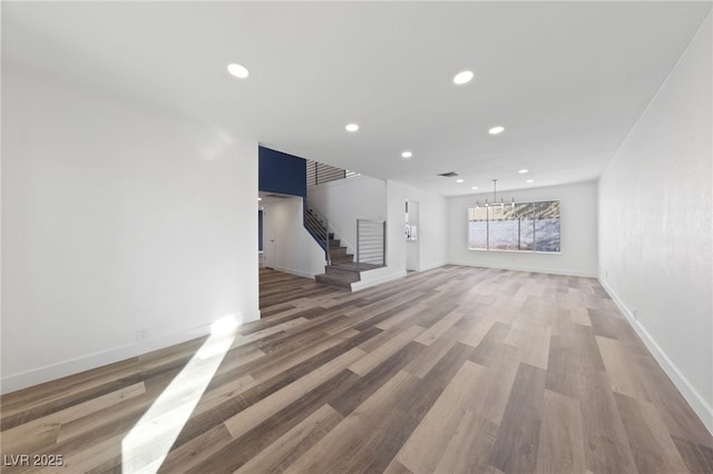 unfurnished living room featuring an inviting chandelier and wood-type flooring