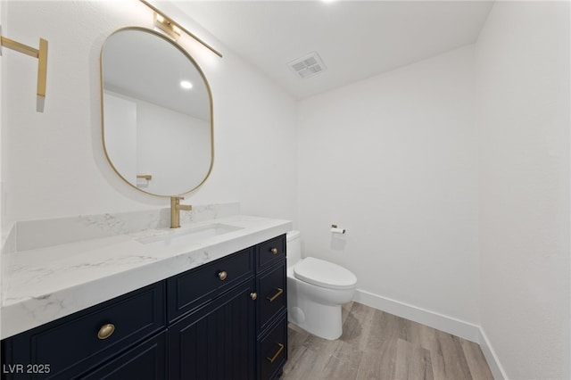 bathroom with toilet, wood-type flooring, and vanity