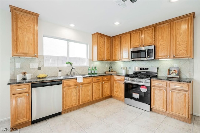 kitchen featuring sink, appliances with stainless steel finishes, dark stone counters, and decorative backsplash