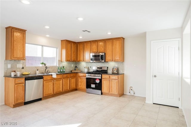 kitchen with stainless steel appliances, tasteful backsplash, dark stone counters, and sink