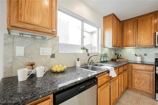 kitchen featuring tasteful backsplash, dark stone countertops, sink, stainless steel appliances, and light tile patterned floors