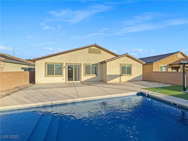 back of property with a fenced in pool and a patio