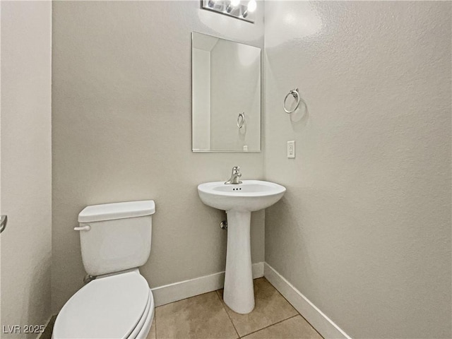 bathroom with toilet, tile patterned flooring, and sink