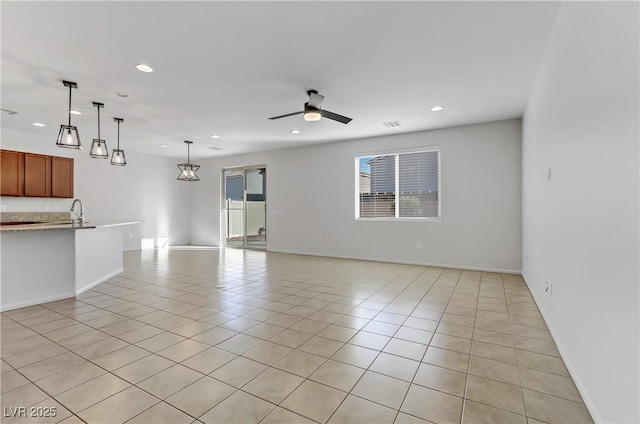 unfurnished living room with ceiling fan, light tile patterned floors, and sink