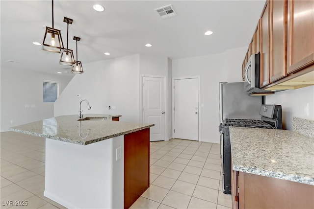 kitchen featuring light tile patterned floors, gas stove, light stone countertops, pendant lighting, and sink