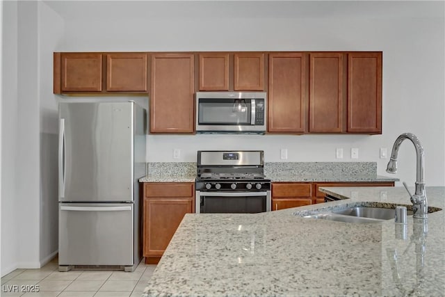 kitchen with light tile patterned floors, appliances with stainless steel finishes, sink, and light stone counters