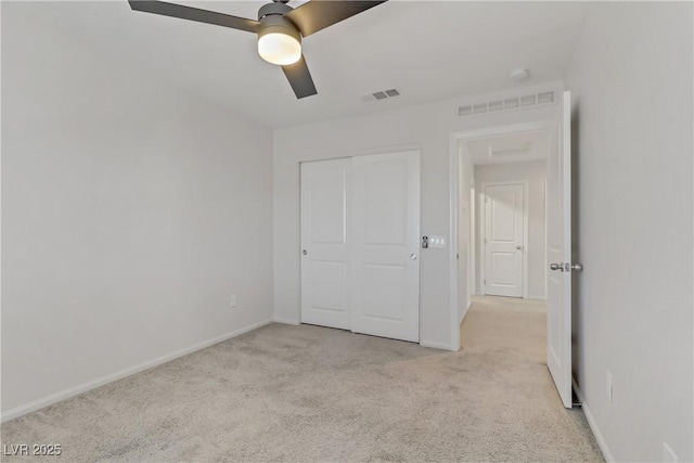 unfurnished bedroom featuring ceiling fan, light carpet, and a closet