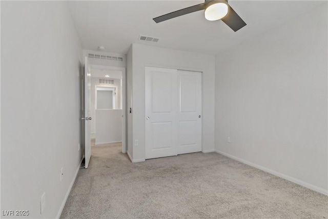 unfurnished bedroom with ceiling fan, light colored carpet, and a closet