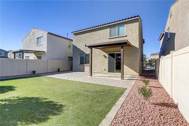 back of property with a lawn and a patio