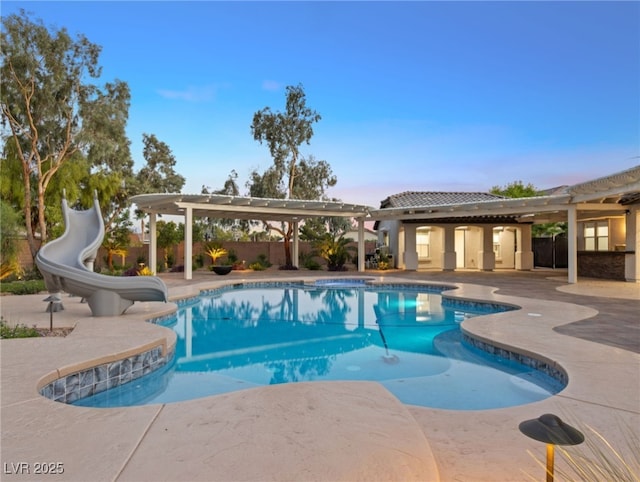 pool at dusk featuring a water slide and a patio