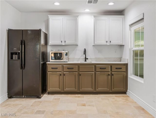 kitchen featuring sink, white cabinets, and black fridge with ice dispenser