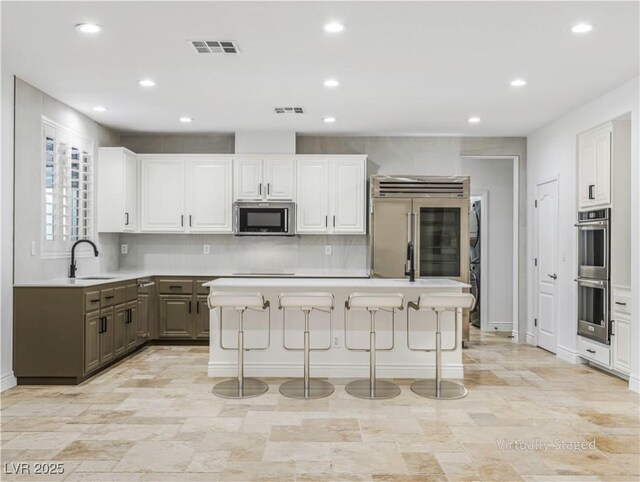 kitchen featuring gray cabinets, a breakfast bar, sink, white cabinetry, and stainless steel appliances