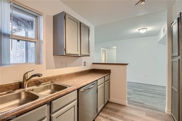 kitchen with stainless steel dishwasher, sink, gray cabinetry, and light hardwood / wood-style flooring