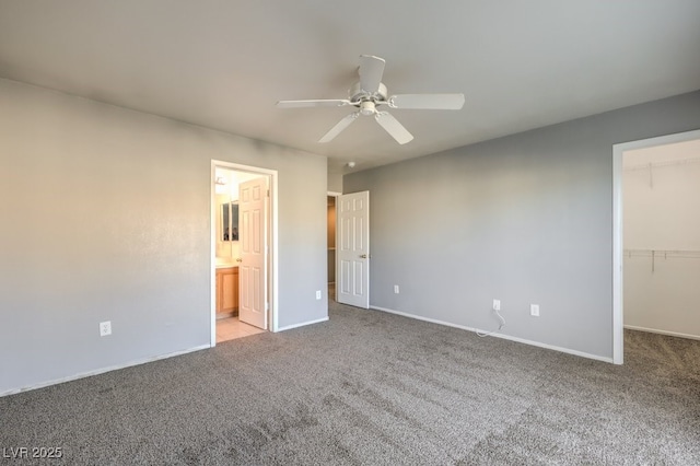 unfurnished bedroom with ceiling fan, connected bathroom, a closet, light colored carpet, and a walk in closet